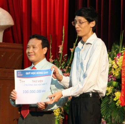 Ông Vũ Hồng Nam - Phó Tổng giám đốc Tập đoàn Gami (bên phải) trao tặng quà và học bổng cho sinh viên Trường ĐHKT.